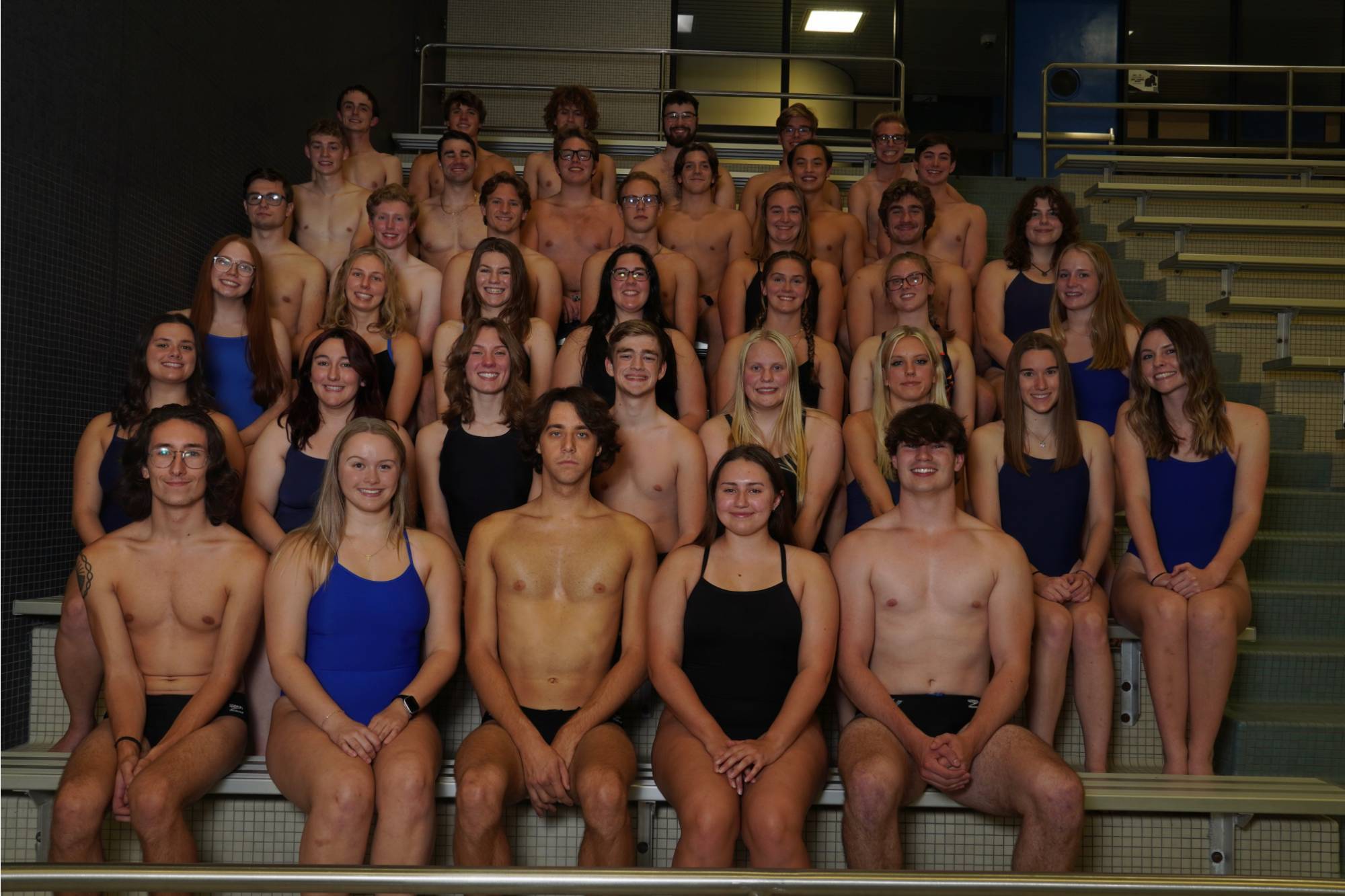 group of swimmers standing on bleachers for a group photo